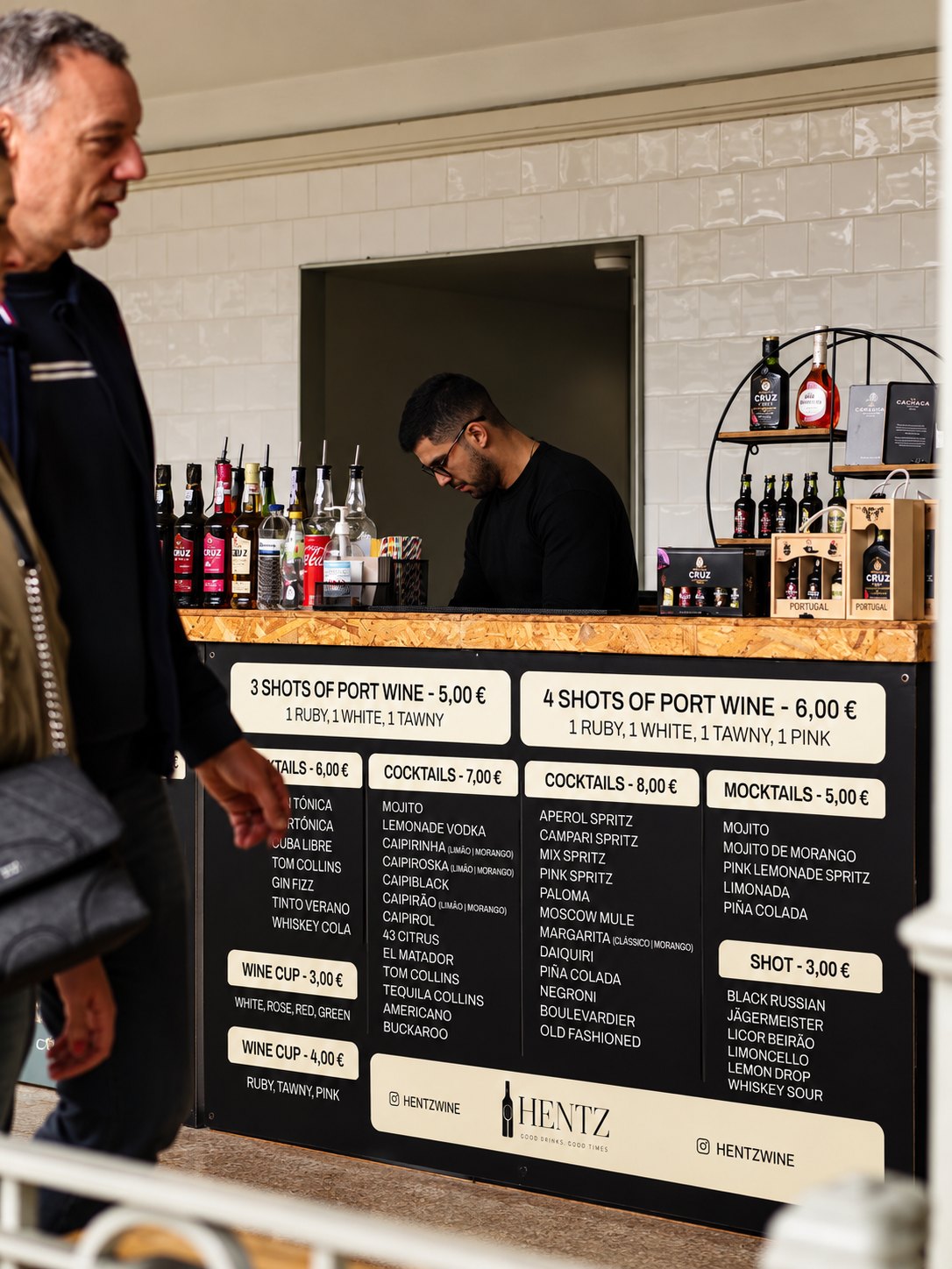 Barman HENTZ a servir cocktails num bar móvel com tabela de preços