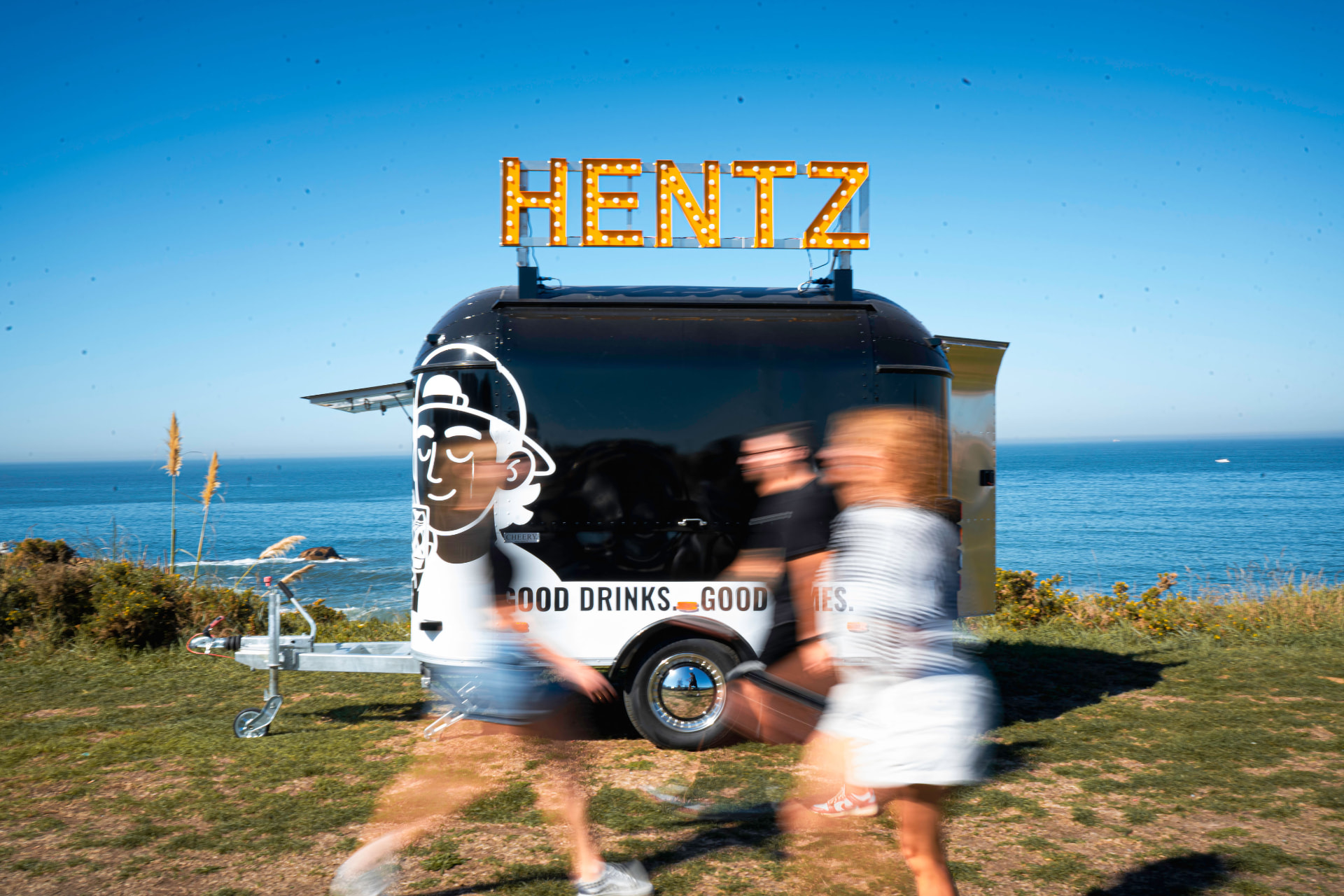 Bar móvel HENTZ junto ao mar, com o letreiro iluminado da marca