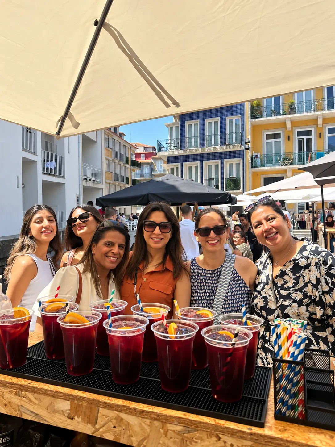 Grupo de clientes com copos de sangria atrás do bar HENTZ numa praça